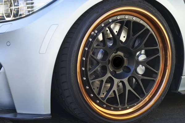 beyaz araba, altın jantlar, siyah lastikleri 