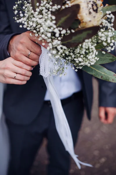 Ruce a prsteny na svatební kytici — Stock fotografie