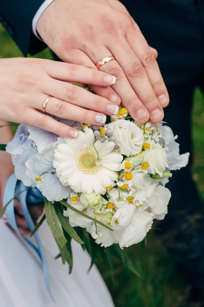 Händer och ringar på bröllopsbukett — Stockfoto