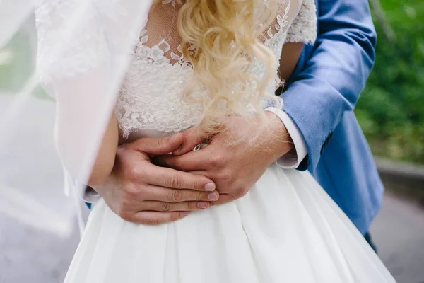 Ο γαμπρός με τα πόδια από το γάμο αγκαλιάζει απαλά στη μέση της νύφης. — Φωτογραφία Αρχείου