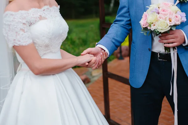 Brud- och brudgummen håller varandra i handen — Stockfoto