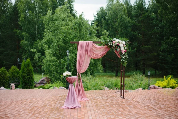 Arco per la cerimonia nuziale. Arco, decorato con bellissimi fiori freschi e stoffa. Colore Bordeaux. Registrazione nel luogo del matrimonio . — Foto Stock