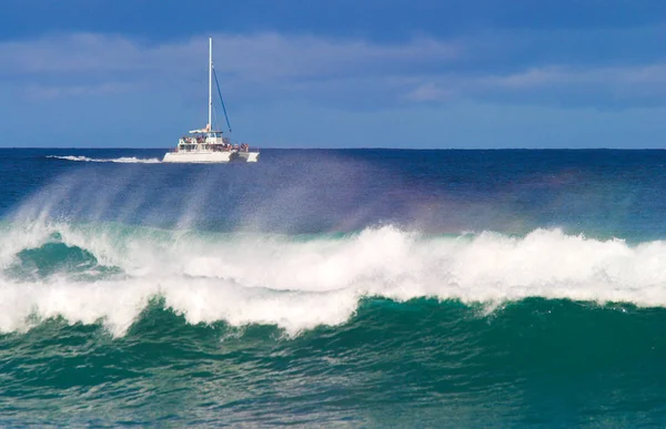 Un catamarán frente a la costa de Kauai con una gran ola en primer plano —  Fotos de Stock