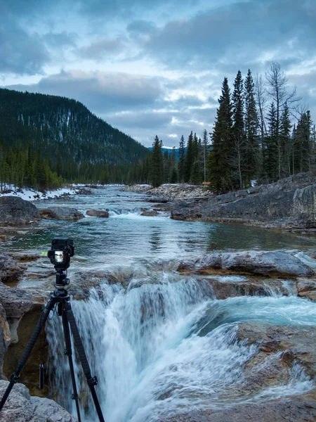 Camera on a tripod setup in front of a waterfall — Stock Photo, Image