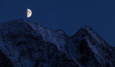 Ay yükseliyor karlı bir dağ üzerinde