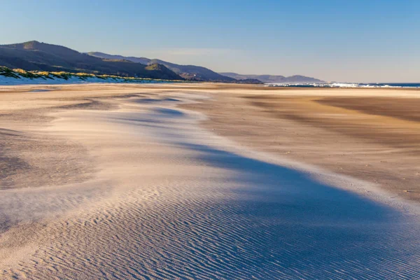 Una duna de arena en una playa con la arena soplada por el viento — Foto de Stock