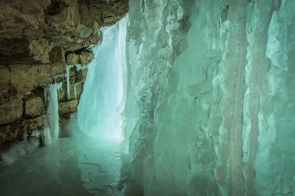 Маленькая пещера со льдом за замерзшим водопадом — стоковое фото