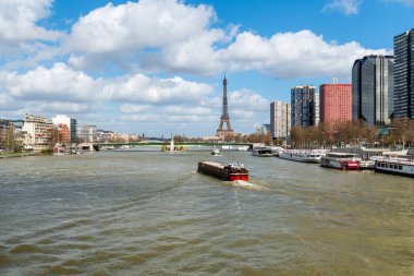 Paris, France - March 13 2020: Barges on Seine river with Eiffel Tower, Liberty Statue, Front de Seine and Pont de Grenelle in the background
