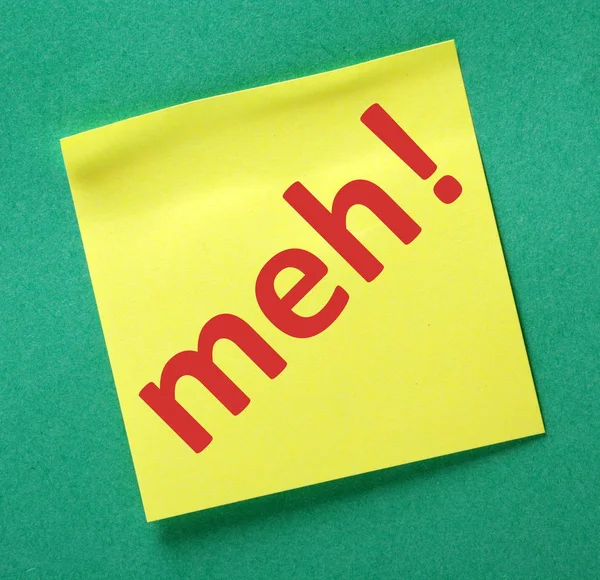 Het woord meh! in rode tekst op een gele kleverige nota — Stockfoto