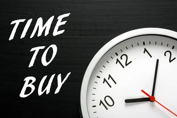 Hora de comprar mensagem em um quadro negro ao lado de um relógio de parede — Fotografia de Stock