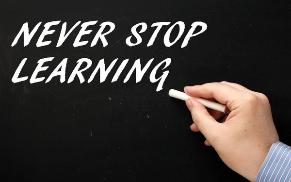 Mano masculina en una camisa de negocios escribiendo las palabras Never Stop Learning en una pizarra — Foto de Stock