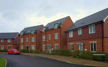 Bracknell, England - Nov 20, 2017: Row of new build red brick homes on a street with a car in the town of Bracknell, England clipart