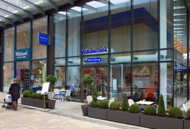 Bracknell, İngiltere - 20 Mart, çocuk arabası olan bir kadın Carluccio'nın Şarküteri ve yemek, Bracknell, İngiltere tarafından insan ile pencereler arasında görünür geçer. Antonio Carluccio restoran zinciri Londra'da 1999 yılında kurulan.