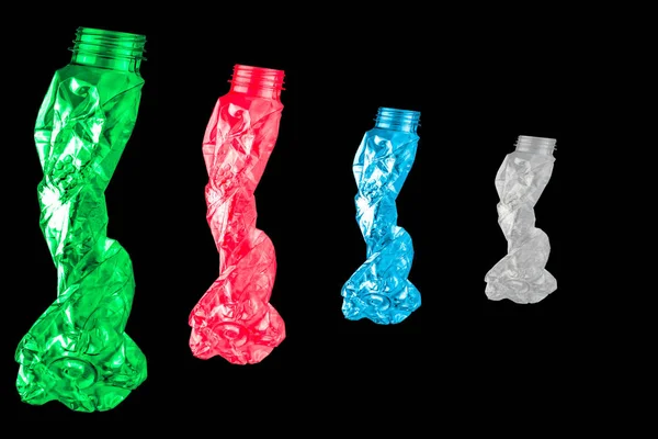 Las botellas de plástico retorcidas verdes, rojas, azules y blancas tienen la forma de cuatro personas caminando en fila sobre fondo negro con espacio para copiar — Foto de Stock