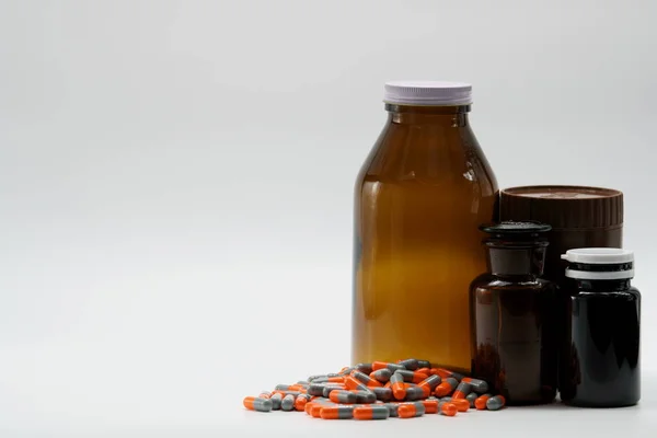 Píldoras de la cápsula antibiótica y botellas de ámbar sobre fondo blanco con espacio de copia y etiqueta en blanco, solo agregue su propio texto. Concepto de resistencia . — Foto de Stock