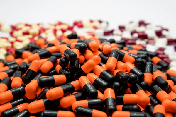 Orange, black, white, red, pale yellow, antibiotic capsule pills, drug resistance concept — Stock Photo, Image