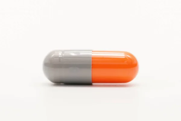 Grey, orange antibiotic medicine capsule pills isolated on white background — Stock Photo, Image