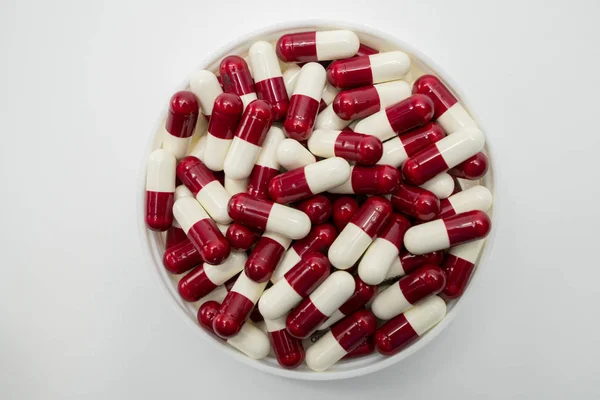Top view of red, white, capsule pills in plastic container on white background — Stock Photo, Image