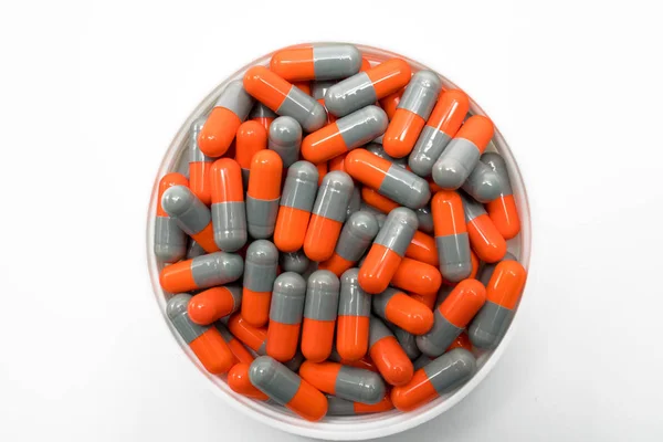 Κάτοψη του γκρι, πορτοκαλί, αντιβιοτικό καψάκιο χάπια σε πλαστικό δοχείο σε άσπρο φόντο. Ναρκωτικών αντίσταση έννοια. — Φωτογραφία Αρχείου