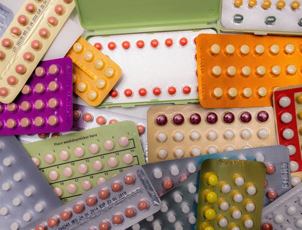 Piles of colorful birth control pills with modern packaging. Family planning concept