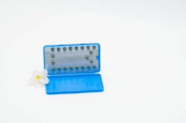 Doğum kontrol hapları ile modern ambalaj ve beyaz arka plan üzerinde çiçek. Aile planlaması kavramı