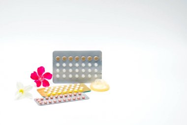 Doğum kontrol hapları ve beyaz arka plan üzerinde pembe çiçek prezervatifle. Aile planlaması kavramı