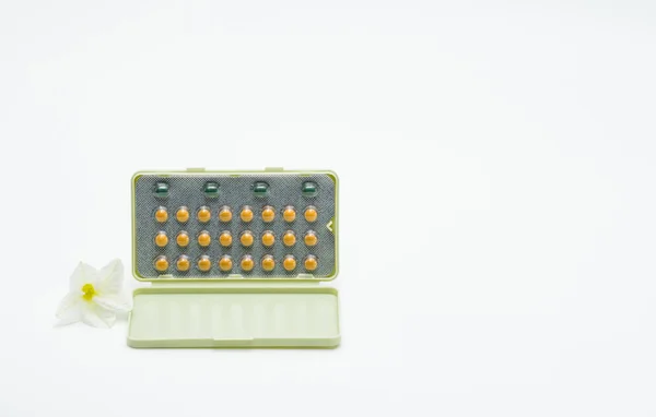 Pastillas anticonceptivas con embalaje moderno y flor sobre fondo blanco. Concepto de planificación familiar — Foto de Stock