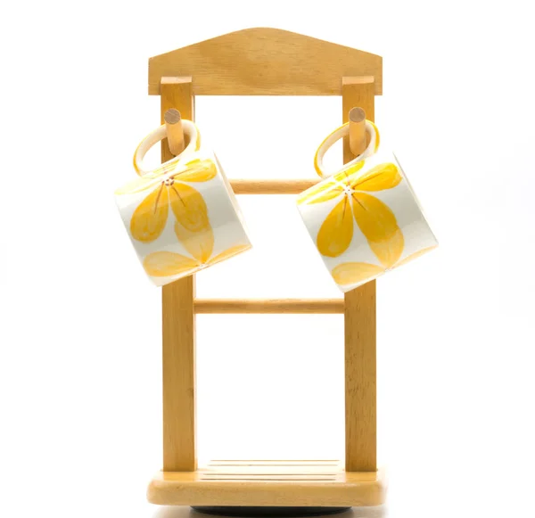 Dois copos de café é pintado flor amarela fora pendurado no cabide de madeira com estilo minimalista isolado no fundo branco — Fotografia de Stock