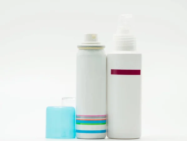 Frasco de pulverização com tampa azul aberta e frasco bomba de cuidados com a pele sobre fundo branco, rótulo em branco — Fotografia de Stock