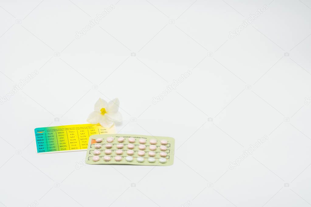 Contraceptive pills with flower on white background. Family planning concept
