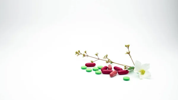 Röd, grön tillägg och vitamin tablett och kapsel piller med blomma och grenen på vit bakgrund med kopia utrymme. — Stockfoto