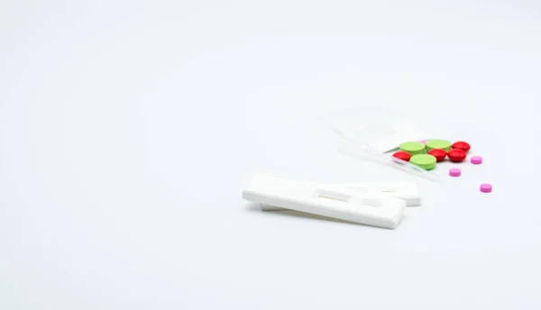 Дві метамфетамінні касети тест і пластиковий крапельниця з червоними, рожевими і зеленими препаратами, підроблені порошки героїну на білому тлі з місцем для тексту — стокове фото