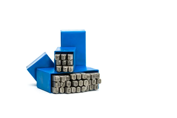 Conjunto de abecedario de sello metálico y punzón numérico en caja de plástico azul aislado sobre fondo blanco con espacio para copiar — Foto de Stock