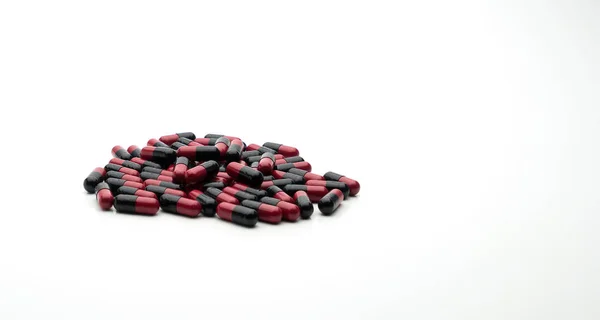 Красный, черный антибиотик капсулы таблетки изолированы на белом фоне с копировальным пространством, концепция лекарственной устойчивости — стоковое фото