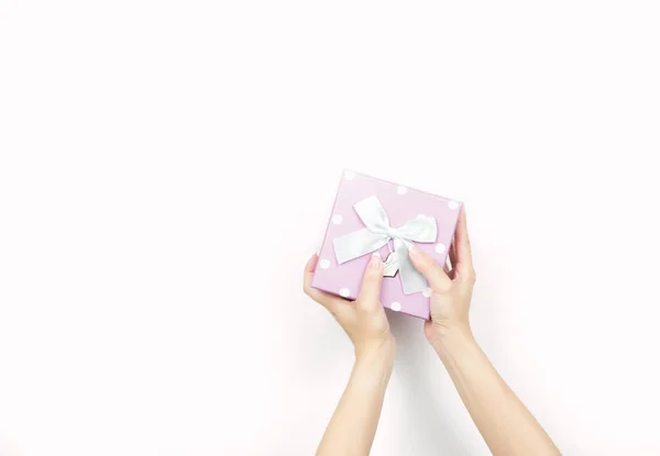 特写美丽和健康女人双手整齐指甲与孤立的白色背景上的波尔卡圆点图案举行粉红色礼品盒 — 图库照片