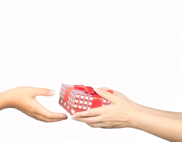 Zbliżenie dłoni dawania i otrzymywania Christmas gift box wrapped z czerwoną wstążką na białym tle — Zdjęcie stockowe