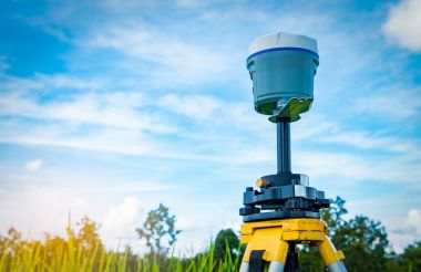 GPS surveying instrument on blue sky and rice field background clipart