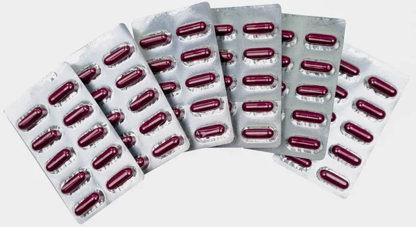 Куча таблеток красных капсул в блистерной упаковке с вырезкой пути. Концепция витаминов и добавок — стоковое фото
