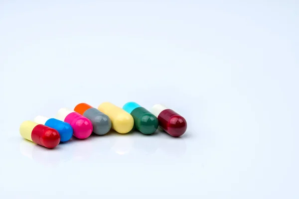 コピー スペースと白い背景の上の行に抗生物質のカプセル錠剤のカラフルです。薬剤耐性、合理的で抗生物質の薬物使用を正常性ポリシーと健康保険の概念. — ストック写真