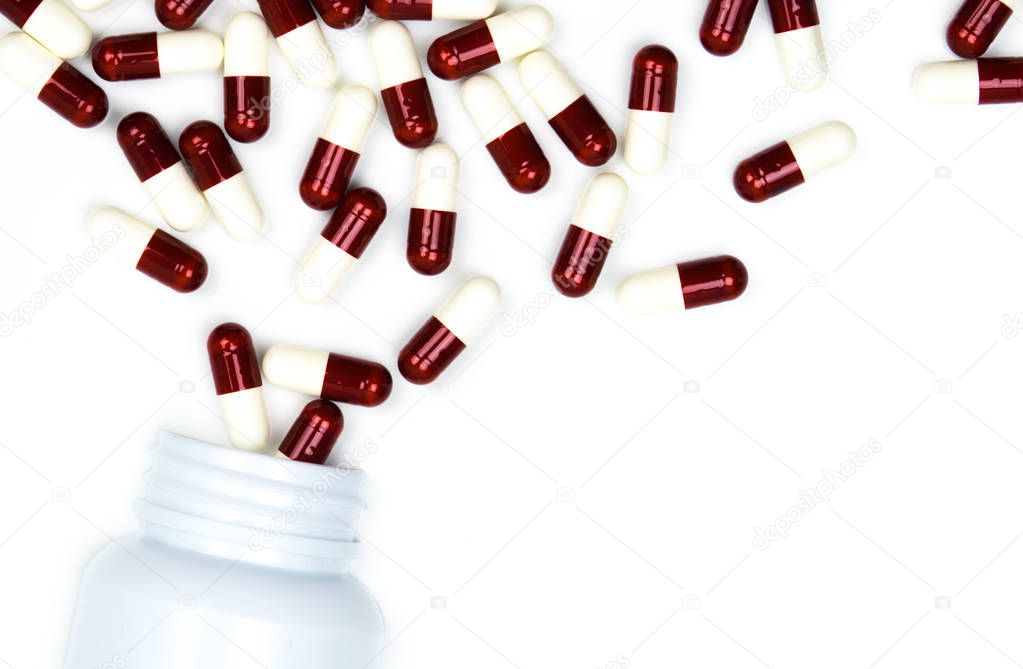 Pouring antibiotics capsule pills into plastic bottle isolated on white background with copy space. Drug storage, antibiotic drug use with reasonable, health policy and health insurance concept.