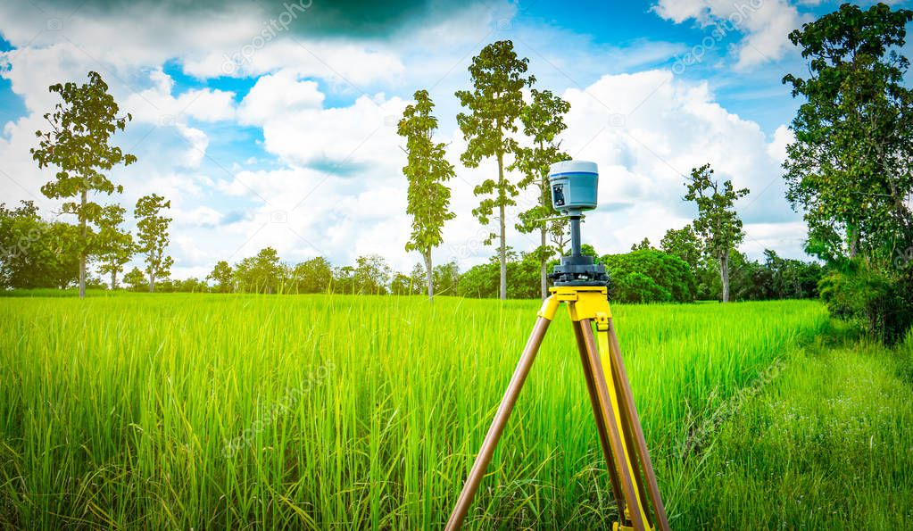 GPS surveying instrument install on tripod in green rice field, Thailand