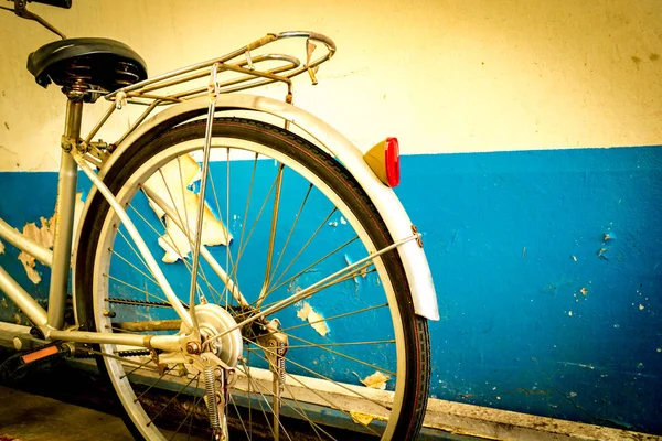 La bicicleta estacionada junto a las viejas paredes de cemento de pintura pelada blanca y azul . —  Fotos de Stock