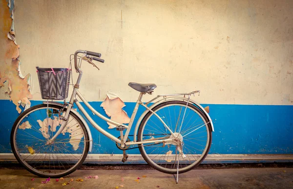 The bike parked next to the old white and blue peeling paint cement walls. — Stock Photo, Image