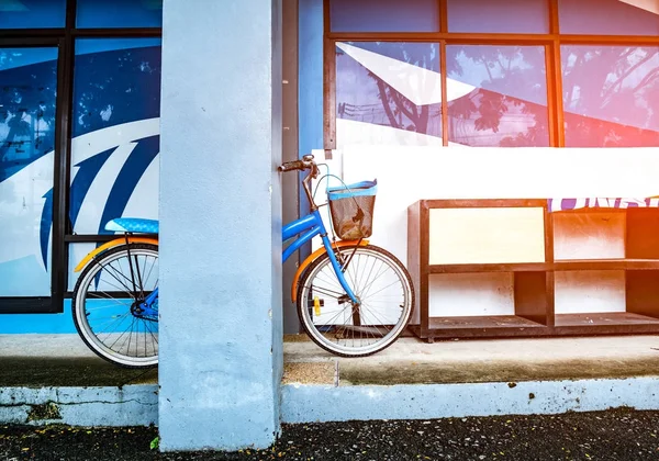 Cykel lutande på en stolpe nära en trä skohylla placeras på en cement våningen i en byggnad med utflytning ljus. Vintage stil. — Stockfoto