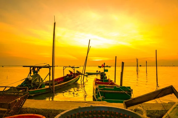 Рибацький човен плаває в морі біля бамбук полюса на заході сонця в Таїланді. — стокове фото