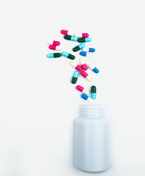 Выливание антибиотиков капсулы таблетки в пластиковую бутылку изолированы на белом фоне с копированием пространства. Хранение лекарств, использование антибиотиков с разумной концепцией медицинского страхования
.