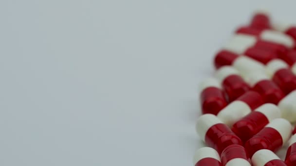 Pillole di capsule di antibiotici rossi e bianchi scorrono e si muovono da destra a sinistra. Concetto di resistenza alla droga. Antibiotici uso di droga con ragionevole. Sanità globale. Industria farmaceutica . — Video Stock