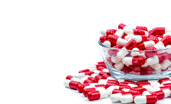Capsules antibiotiques rouges, blanches pilules dans un bol en verre et certaines sur fond blanc avec espace de copie. Concept de pharmacorésistance. Utilisation d'antibiotiques avec un concept de soins de santé raisonnable et global . — Photo