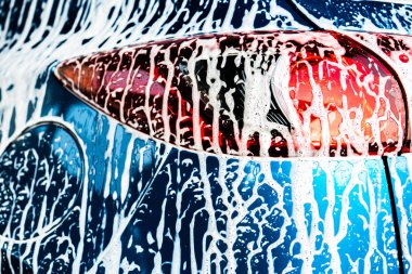 Arkadan mavi kompakt Suv araç spor ve modern tasarım sabunla yıkama ile görünüşü. Araba beyaz köpükle kaplı. Araç Bakım Servisi iş kavramı.