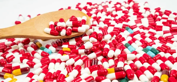 Kolorowe tabletki antybiotyk kapsułki i drewniane łyżki na białym tle. Pojęcie oporu narkotyków. Zażywanie antybiotyków z rozsądnym i globalnej koncepcji opieki zdrowotnej. — Zdjęcie stockowe